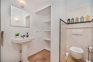 A bathroom with a sink and a toilet with houses on the wall