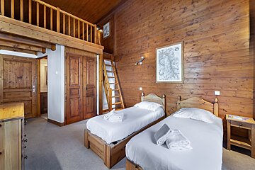 A wooden bedroom with two beds and a ladder
