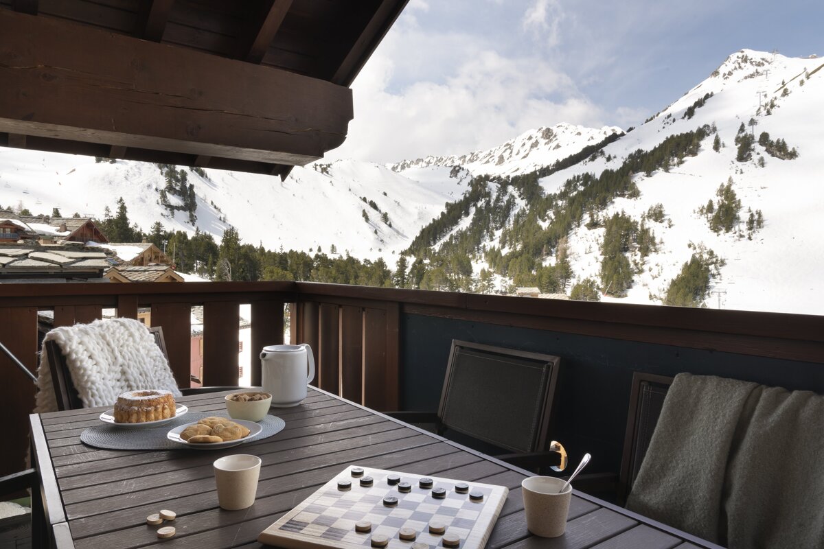 A chess board sits on a table with mountains in the background