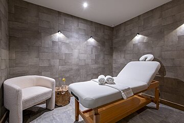 A massage table in a room with a chair
