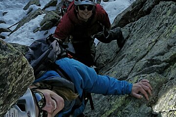 two people climbing on a snow outcrop of rock
