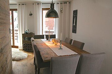 A dining room with a long wooden table and chairs