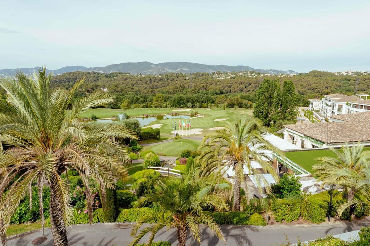 An aerial view of a golf course with palm trees and mountains in the background
