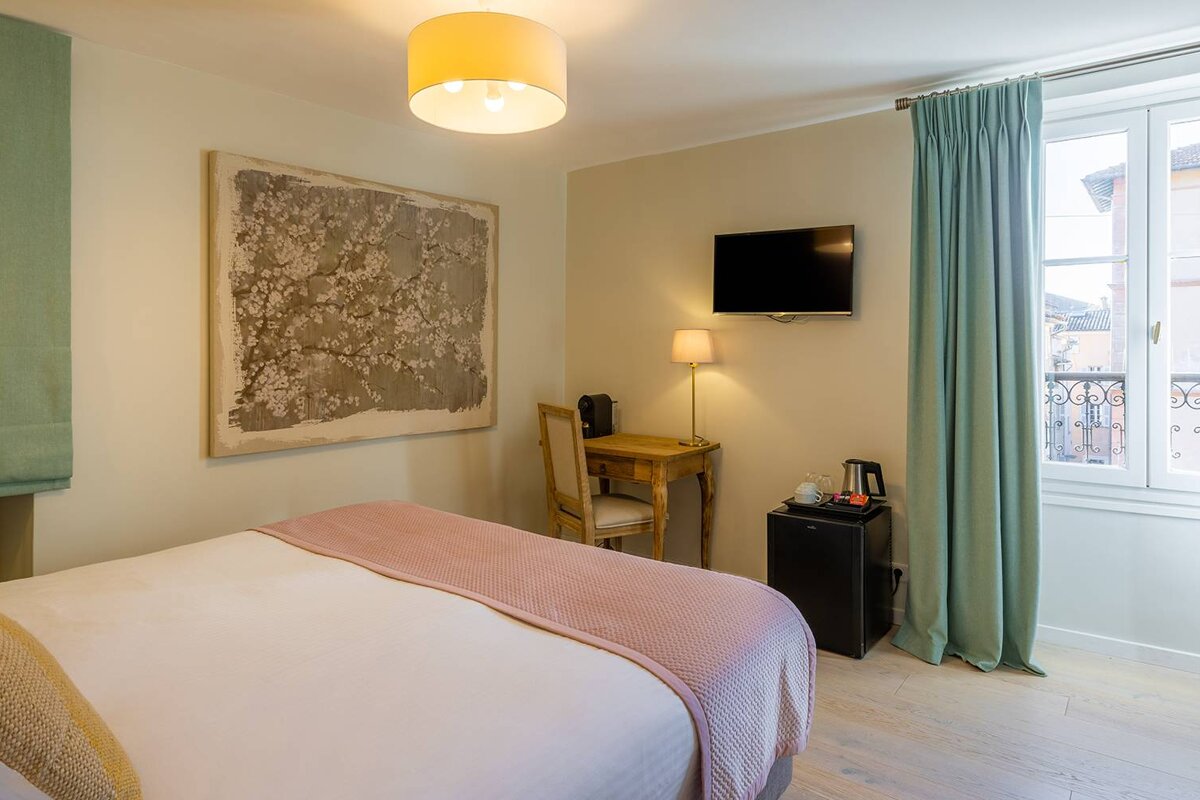 A bedroom with a bed a desk and a flat screen tv