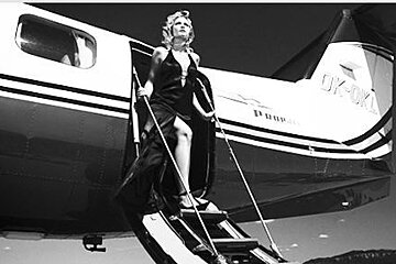A woman in a black dress is standing on the steps of an airplane