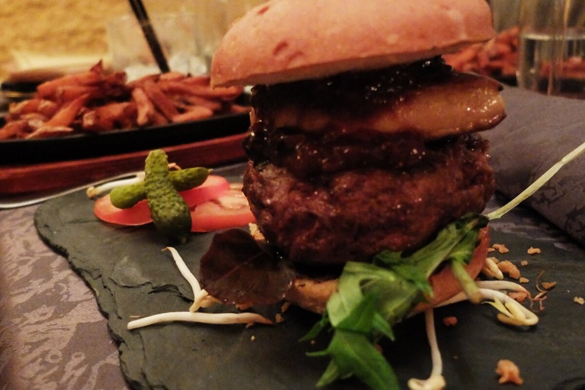 a stacked up burger on a black slate