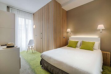 A hotel room with a white bed and green pillows