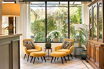 A room with yellow chairs and ottomans in front of a window