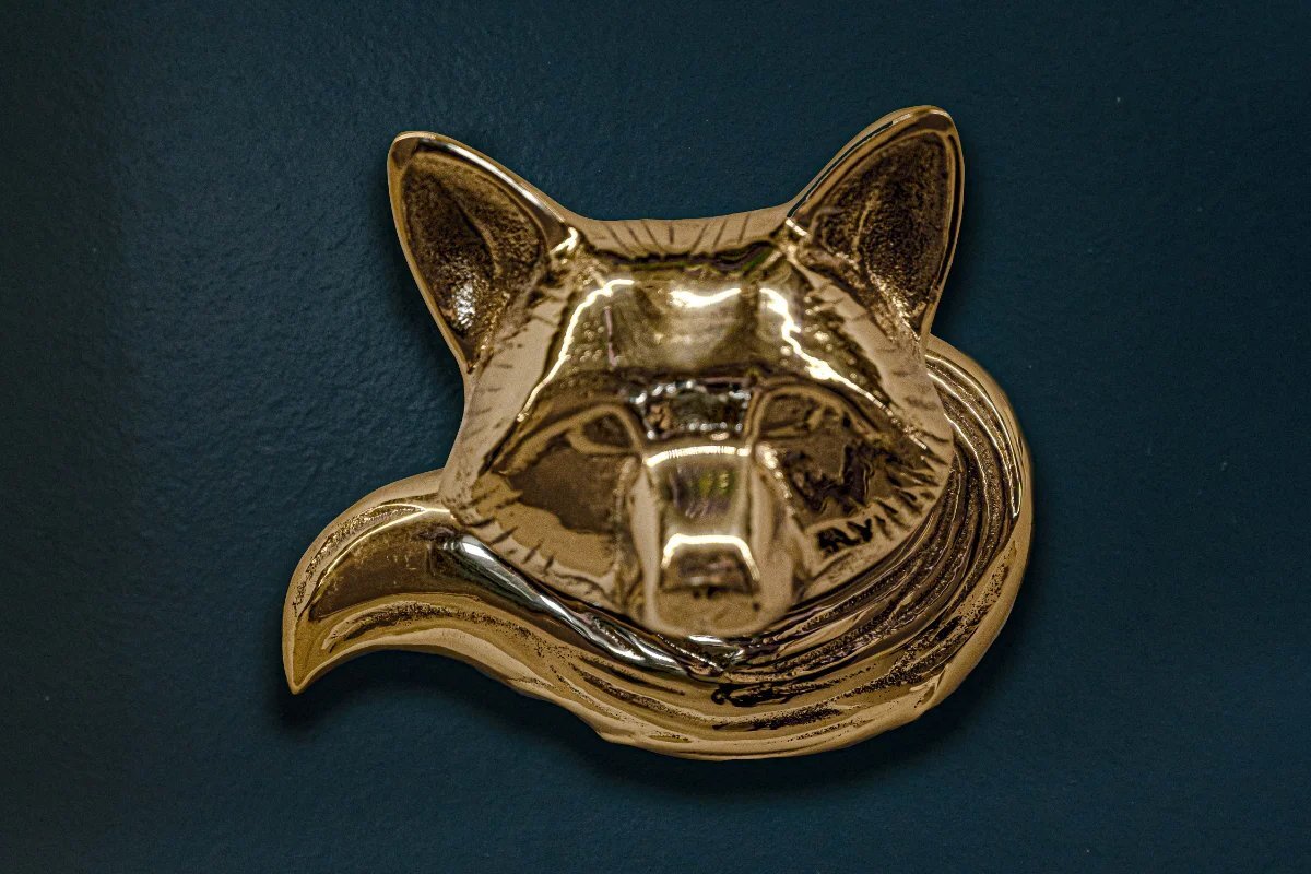 A close up of a gold fox head on a blue background