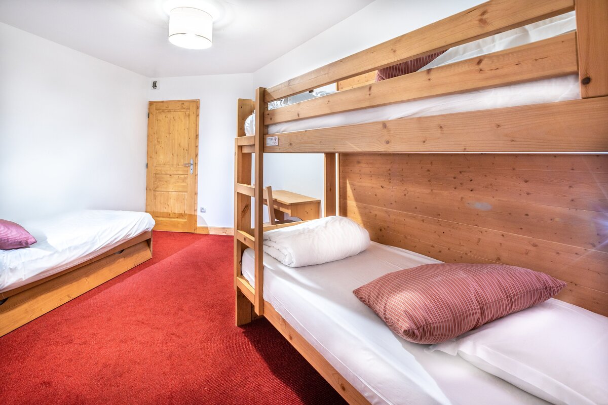 Three bunk beds in a room with a red carpet