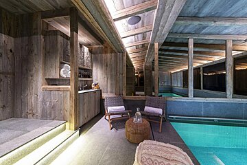A room with chairs and a table in front of a pool