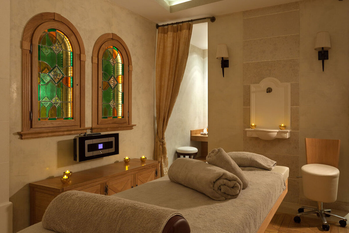 A room with two stained glass windows and a bed with towels on it