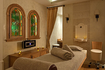 A room with two stained glass windows and a bed with towels on it
