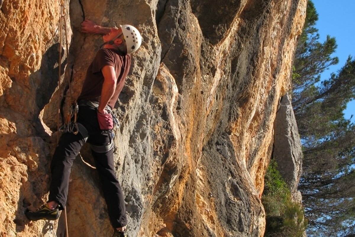 a picture of a man climbing on a rock face with a white helmet on