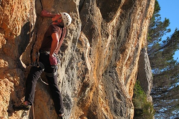 a picture of a man climbing on a rock face with a white helmet on