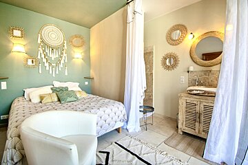 A bedroom with a bed a chair and a mirror