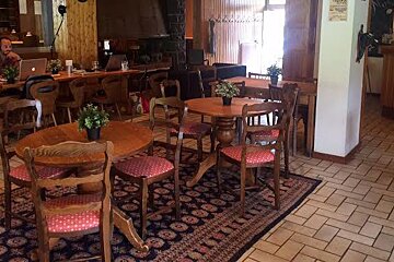 A man is sitting at a table with a laptop in a restaurant