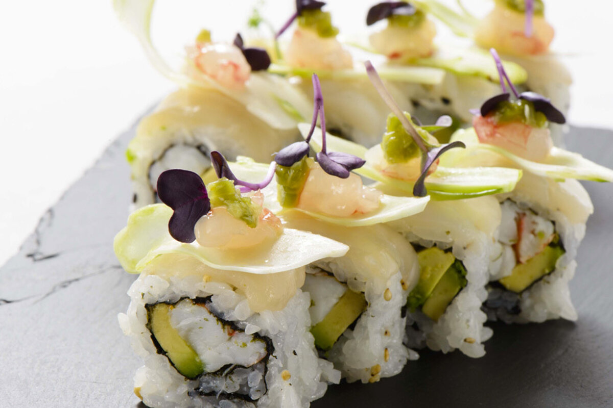 A close up of a sushi roll with shrimp and avocado