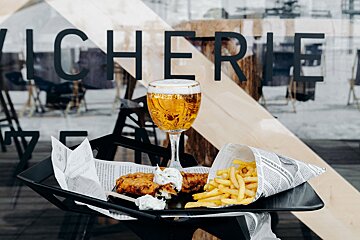A glass of beer sits next to a tray of french fries