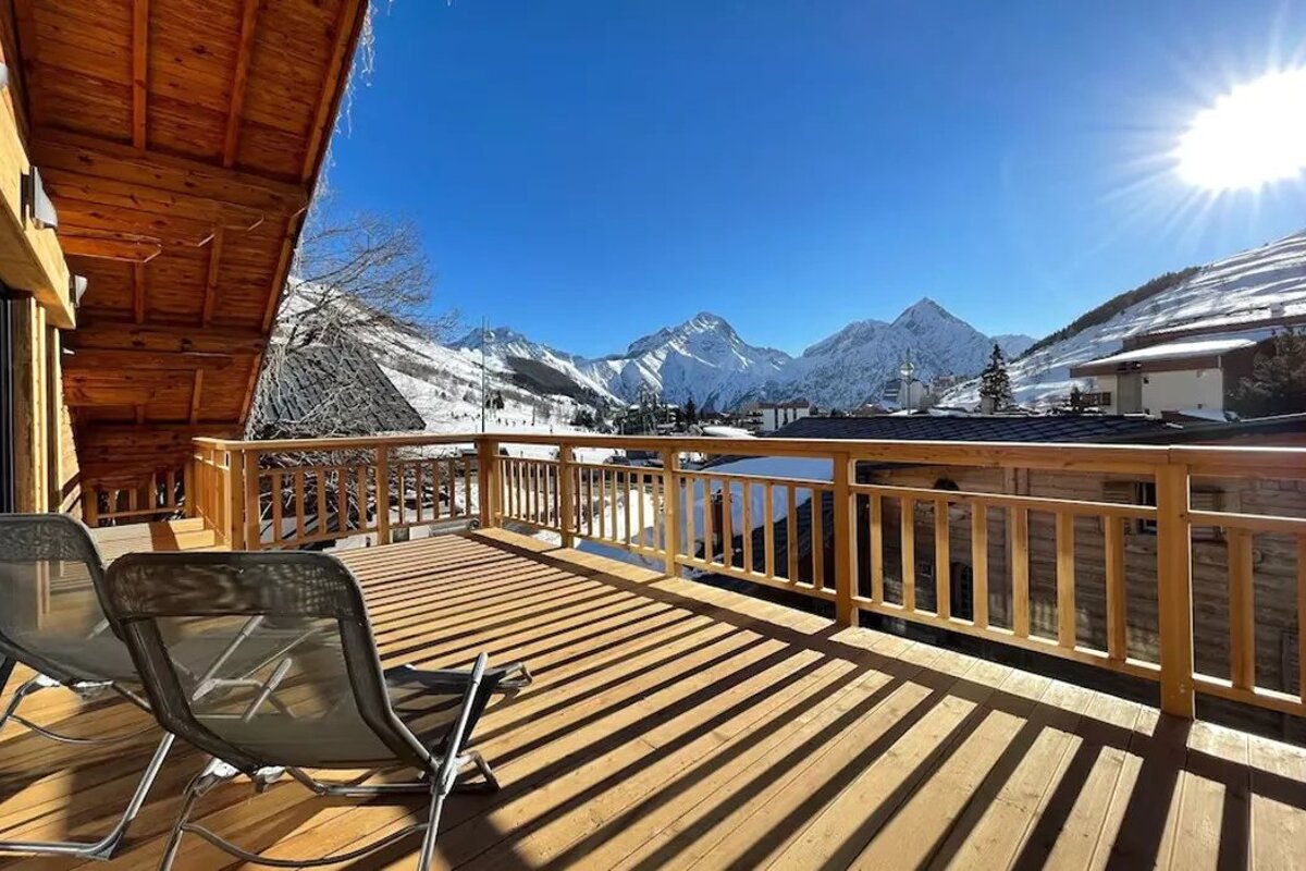A balcony with chairs and a view of snowy mountains