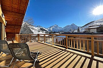 A balcony with chairs and a view of snowy mountains