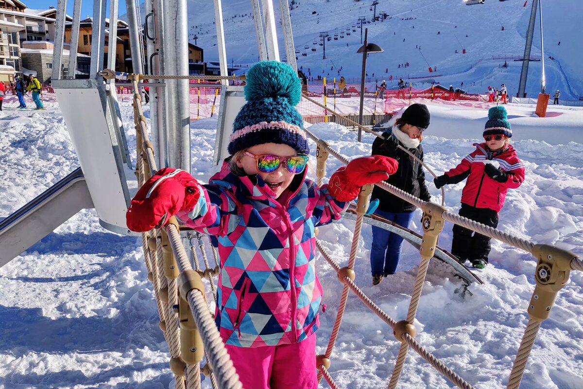 A little girl wearing sunglasses is playing in the snow