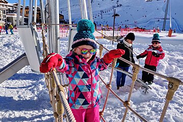 A little girl wearing sunglasses is playing in the snow