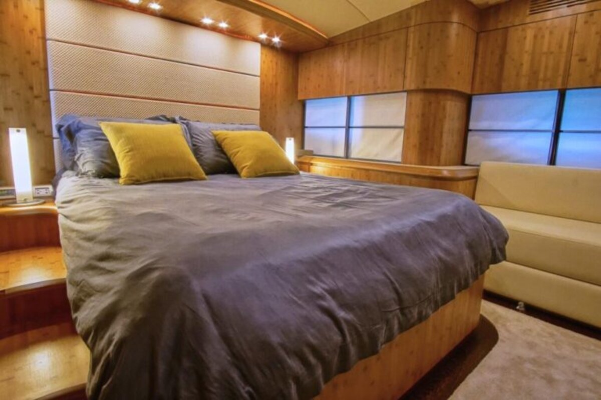 A bed with a gray comforter and yellow pillows