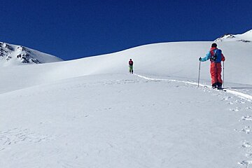 two people breaking trail up a snow covered bowl