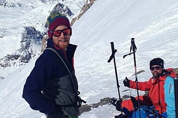 two skiers taking a break at the top of a ridge