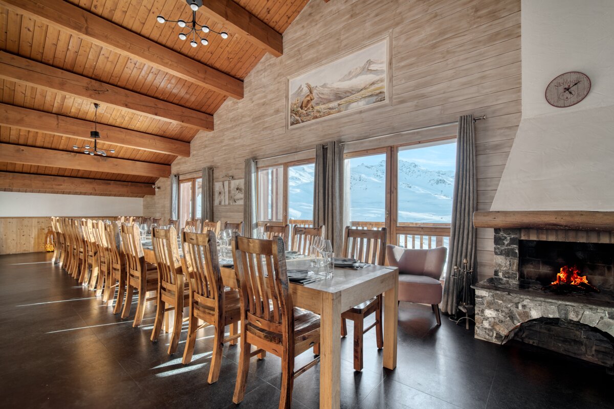 A large room with a long table and chairs and a fireplace