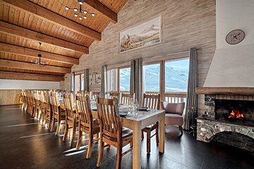 A large room with a long table and chairs and a fireplace