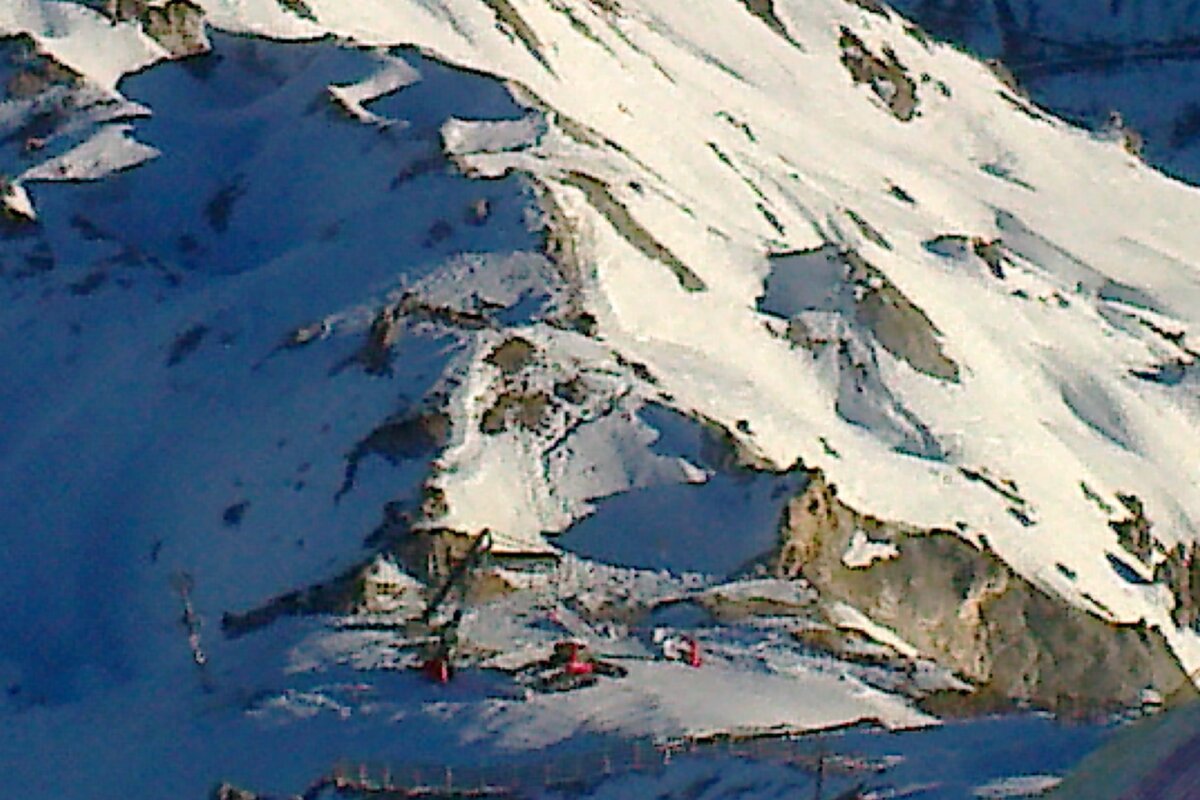 A snowy mountain with a red ski lift in the foreground