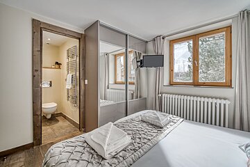 A bedroom with a toilet and a television on the wall