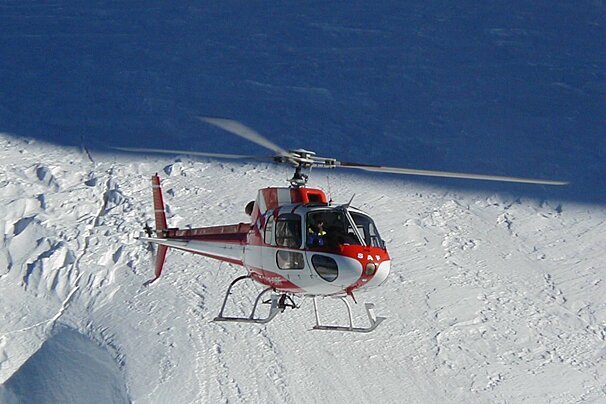 helicopter flying over glacier