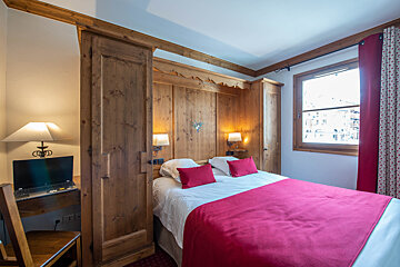 A bedroom with a bed and a laptop on a desk