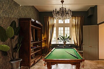 A pool table in a room with a chandelier above it