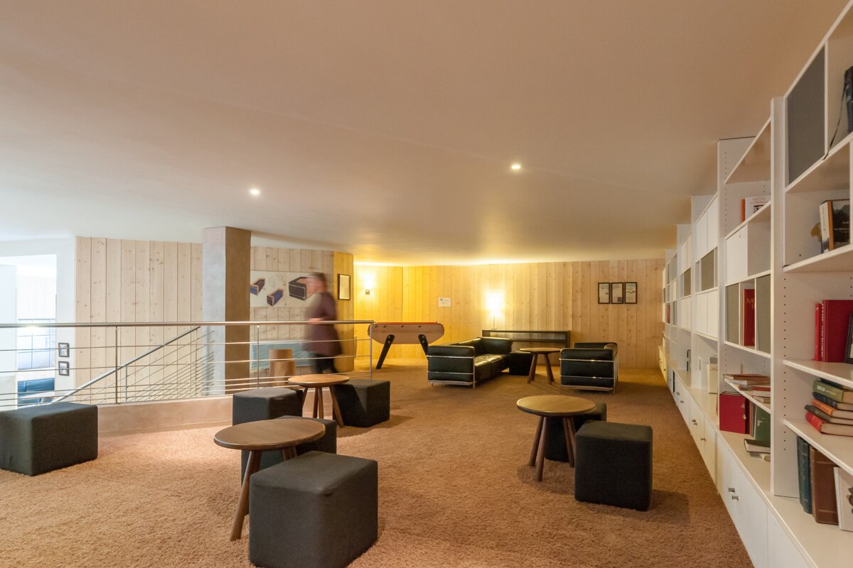 A man is walking through a room with tables and chairs