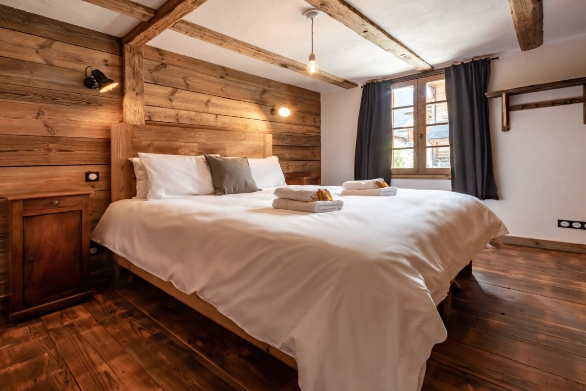 A bed with white sheets and pillows in a bedroom
