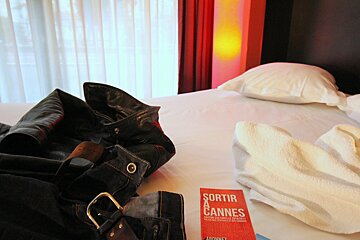 A red book titled sortir de cannes sits on a bed