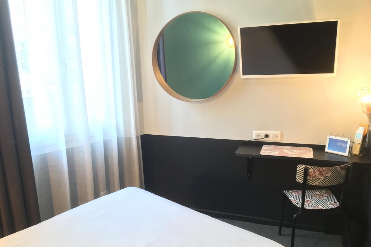 A small room with a bed and a desk with a sign that says ' ariel ' on it