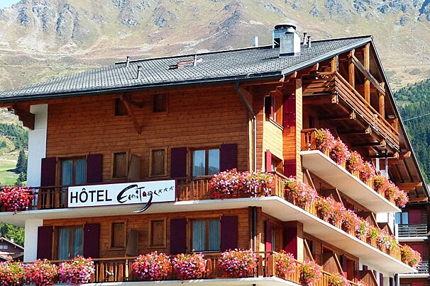 A hotel with mountains in the background and flowers on the balconies
