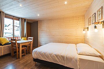 A bedroom with a bed and a table and chairs