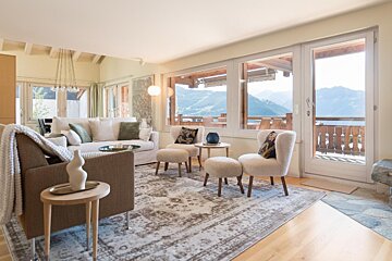A living room with a couch and chairs with a view of the mountains