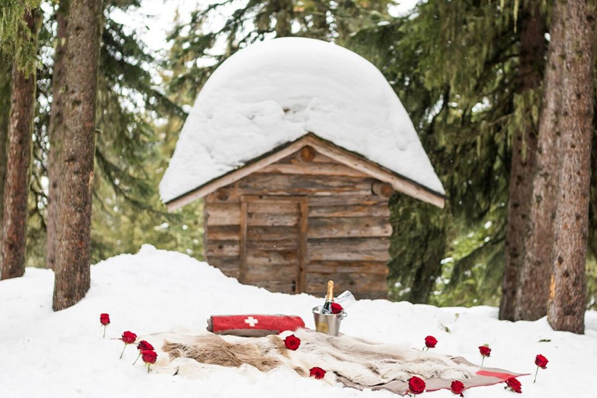 A bucket of champagne sits in front of a snow covered cabin