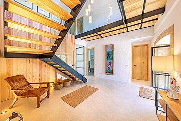 A wooden staircase with a glass railing in a hallway