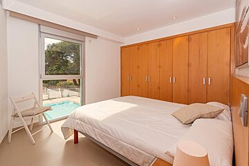 A bedroom with a bed and a chair with a view of a pool
