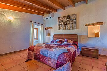 A bedroom with a painting on the wall above the bed
