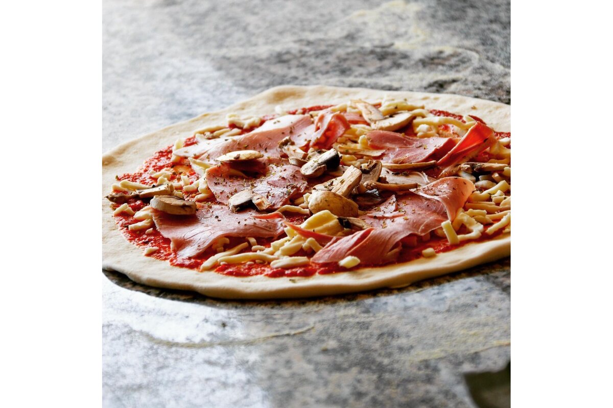 A pizza with ham mushrooms and cheese on it