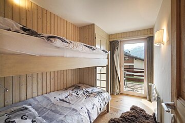 A bedroom with a bunk bed and a window